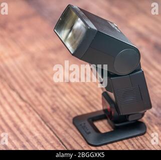 Norwich, Norfolk, UK – April 19 2020. Close up and selective focus of a classic manual Canon flash gun on wooden table Stock Photo
