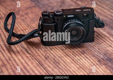 Norwich, Norfolk, UK – April 19 2020. Front on view of Fuji X100V fixed lens range finder style digital camera on a wooden table Stock Photo