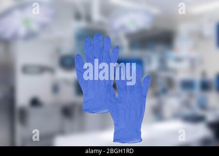 Coronavirus protective measures. Close-up of a pair of blue medical doctor gloves or surgical gloves on a blurred background of a modern hospital inte Stock Photo