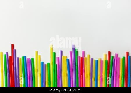 Disposable plastic multicolored tubules for drinks lined up in row on white background, copy space. Festive concept, party, birthday. Flat lay, top vi Stock Photo