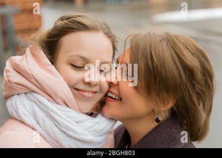 mature mother hugs and kisses her adult daughter on the forehead, girl smiling. family relationship concept Stock Photo