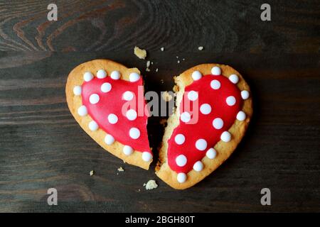 Broken red and white heart shaped royal icing cookie on dark color background Stock Photo