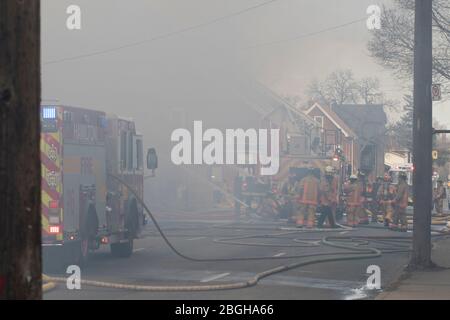 Brigade of firefighters and fire truck battling large structure fire in the city. Teamwork fighting house fire. Stock Photo