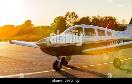 A Piper Archer III general aviation aircraft taxis by in the late afternoon sun. Stock Photo