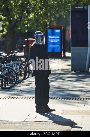London, UK. 21st April 2020.    A Security Guard in a full face mask marshals  the queue outside a supermarket in London.  Credit: Thomas Bowles/Alamy Live News Stock Photo