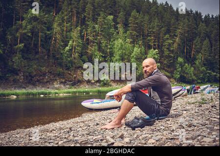 Tourist bearded man resting on the river. Stop and relax while traveling in nature. Stock Photo