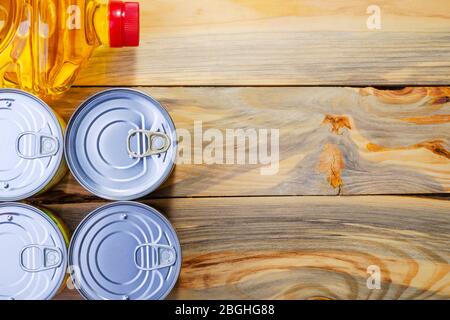Canned food and oil lay in for donation are collected and lies on wooden table. Top view, flat lay. Copy space for text. Close-up. Indoors. Stock Photo