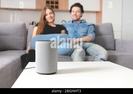 Couple talking command to smart speaker. Intelligent assistant in smart home system. Stock Photo