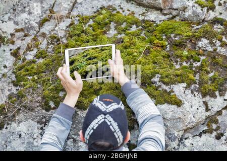 ZAPORIZHZHYA, UKRAINE - JUNE 28, 2018: A man taking picture of moss on a rock using a tablet during PhotoCamp Ukrainian photographers annual meeting o Stock Photo