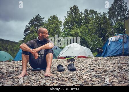 Tourist bearded man resting on the river. Stop and relax while traveling in nature. Stock Photo