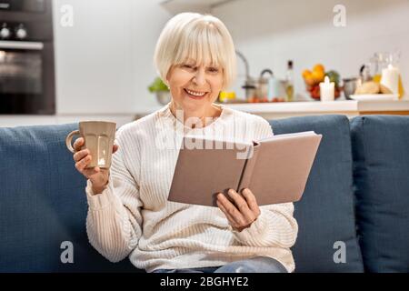 Retirement woman spending weekend at home, reading book Stock Photo