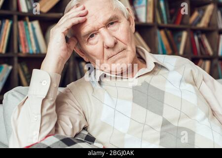 Senior man alone sitting at library tired Stock Photo