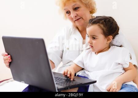 Smart little girl grandchild sit on couch shopping online with excited senior grandmother, teen granddaughter and smiling granny buy on internet Stock Photo