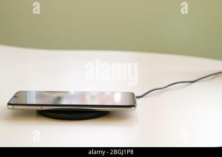 Smartphone wireless charging on induction charger. Wireless charger. Copy space Stock Photo