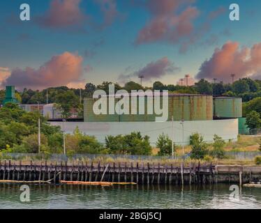 Old, rusty, green industrial tanks on the edge of the sea Stock Photo