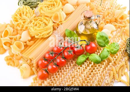 Pasta with fresh tomatoes, basil and olive oil on light shabby rustic background, top view, border. Pasta with ingredients for cooking. Italian food. Stock Photo