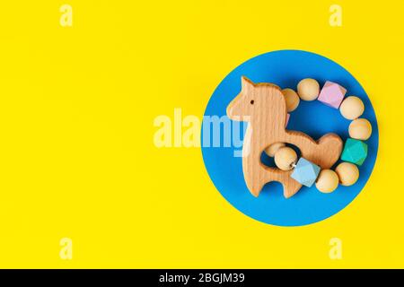 Baby kid educational natural eco zero waste wooden rattle toy on yellow and blue background Stock Photo
