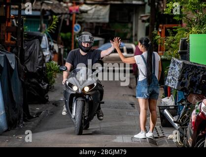 motorcyclist giving a "high five" to woman in back alley Stock Photo