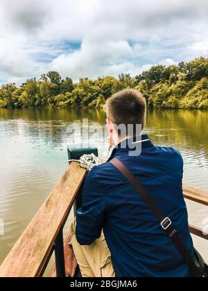 young boy on the bow of a wooden boat having a drink Stock Photo