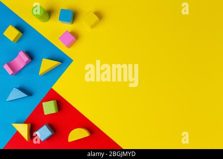 Wooden colorful blocks on geometric yellow blue red background. Top view Stock Photo