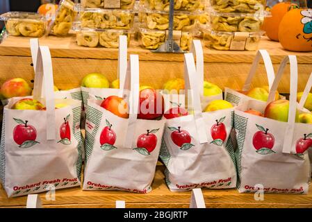 Bags of Fresh Apples and Containers of Sliced Dried Apples on Shelves in Farmers Market Stock Photo