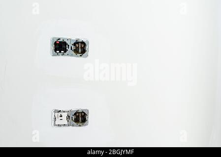 Electrical sockets and switches with the internal circuitry visible on a wall during renovation work. Stock Photo