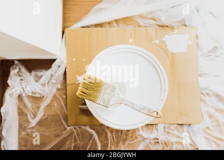 Brush with white paint on a bucket of plastic paint without odors, ecological. Stock Photo