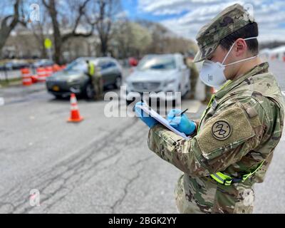 New York Army National Guard Spc. Cody Roche, assigned to the 1st Battalion, 258th Field Artillery, part of the 27th Infantry Brigade Combat Team, records the total vehicle and personnel count that enter through the Entry Control Point of the Bronx-Lehman COVID-19 Testing Site on April 4, 2020. Roche is part of a statewide effort of almost 2,900 members of the New York National Guard responding to community needs to mitigate the effects of the COVID 19 pandemic. U.S. National Guard photo by 1st Lt. Kyle Kilner. Stock Photo