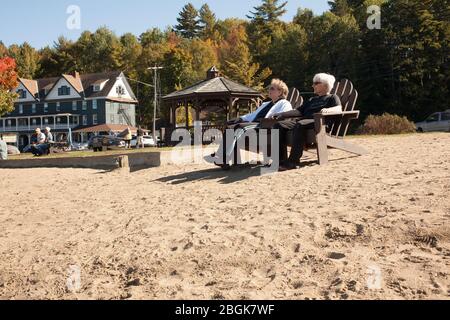 Two elderly women enjoy a day at the upstate New York Long Lake, with Adirondack Hotel in background. Stock Photo