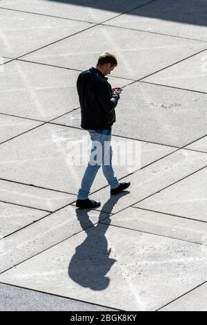 Man looking at smartphone while walking Stock Photo