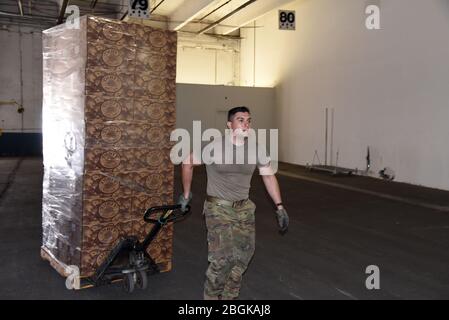 Staff Sgt. Alexis Yanez Valdez utilizes a hand pallet truck to move donated food from a truck into a local warehouse March 30, 2020, Phoenix. The Arizona National Guard activated more than 700 Arizona Citizen-Soldiers and Airmen to support grocery stores, food banks and other community needs during this state of emergency response (U.S. Air National Guard photo by Tech. Sgt. Michael Matkin). Stock Photo