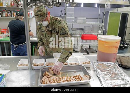 Alaska Army National Guard Sgt. David Osmanson, assigned to the AKARNG Recruting and Retention Battalion, prepares sliced turkey entrees for prepackaged hot lunches in the kitchen at Bean's Cafe in Anchorage, Apr. 8, 2020. 'We couldn't do what we're doing without these Soldiers' help,' said Scott Lingle, Food Service director of Bean's Cafe. 'We appreciate the labor, the attitude and the willingness to help.' (Alaska Army National Guard photo by Sgt. Seth LaCount/Released) Stock Photo