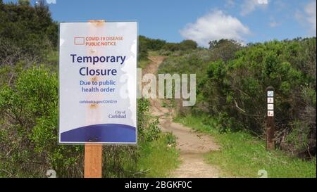 A sign at a nature reserve trailhead informs of temporary closure due to social distancing regulations. Stock Photo