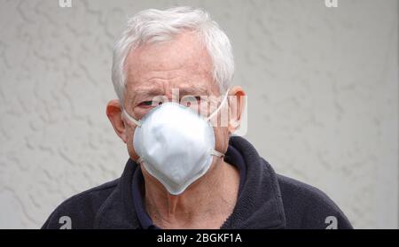 Distressed looking senior (80 year old Caucasian man) wearing a face mask to protect himself from Coronavirus Stock Photo