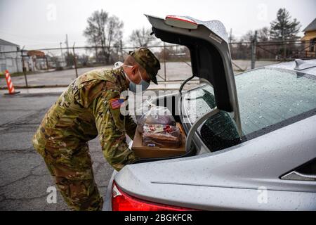 U.S. Army 2nd Lt. Stephen Reid, a Soldier assigned to the Ohio National Guard’s HHC 1-148th Infantry Regiment – 37th Infantry Brigade Combat Team, loads a meal box into a community member’s vehicle at a Toledo Northwestern Ohio Food Bank facility in Toledo, Ohio, April 7, 2020. The food bank provided pre-registered community members the opportunity to drive up and receive a meal box, which can feed a family of two for multiple days. More than 500 Ohio National Guard members were activated to provide humanitarian missions in support of COVID-19 relief efforts, continuing the Ohio National Guard Stock Photo