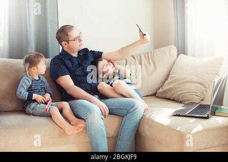 Father and his children are talking online by phone with relatives or friends. Online communication, remote communication. Stock Photo