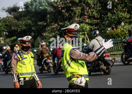 Bandung, Indonesia. 22nd Apr, 2020. Indonesian police officers control traffic during the implementation of the large-scale social restrictions at a checkpoint in Cibiru Bandung. Large-scale social restrictions (PSBB) in the City of Bandung, Cimahi City, and Sumedang Regency, West Java came into force today until May 5, 2020 to stem the wide spread of COVID-19. Credit: SOPA Images Limited/Alamy Live News Stock Photo