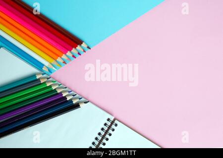 Color pencils and notebook on color background. Stock Photo