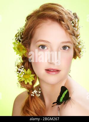 portrait of beautiful healthy redhead teen girl with flowers in her hair holding butterfly on her shoulder Stock Photo