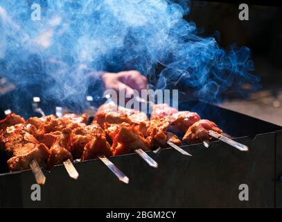 Marinated barbecue meat on skewer. Shish kebab or Shashlyk meaning skewered  meat. Beef or pork on grill on an open fire with smoke. Street food, picnic  concept Stock-foto