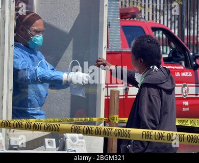 Los Angeles, United States. 22nd Apr, 2020. A woman administers a COVID-19 self-testing kit at a LA Fire Department pop-up testing station, where workers in hazmat suits handed out testing swabs to the homeless from behind a protective window on Tuesday, April 21, 2020. Forty-Three more people have tested positive for the coronavirus at the Union Rescue Mission, Los Angeles' oldest and largest homeless shelter. The sudden spike in cases comes despite the extreme precautions the shelter has been taking to prevent such an outbreak. Photo by Jim Ruymen/UPI Credit: UPI/Alamy Live News Stock Photo