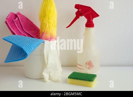 Container with cleaning items on the white table against white wall Stock Photo