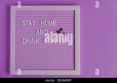 Quote stay home and drink coffee on purple decorative board.  decoratin with  coffee beans. Typography board for interior decoration Stock Photo