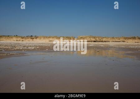 Newton beach near the end of the Black Rocks with reflections in damp sand and an unusually clear sky Stock Photo