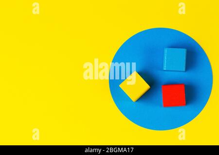 Wooden colorful blocks on geometric yellow blue background. Natural educational zero waste wood toys. Top view Stock Photo