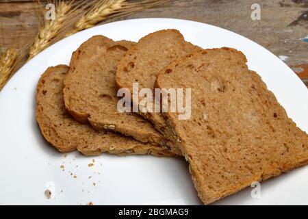 Fresh four multi grain breads in a white ceramic plate on wooden background Stock Photo