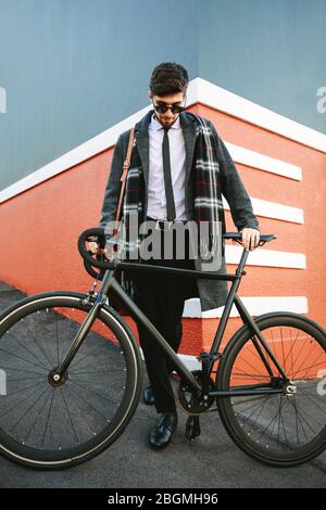 Stylish businessman going to work by bike. Man standing by his bicycle on road. Stock Photo