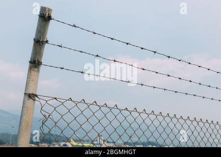 A fence with barbed wire against the sky, a fence with a mesh slave Stock Photo