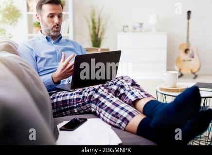 Man working on computer and wearing pajamas Stock Photo