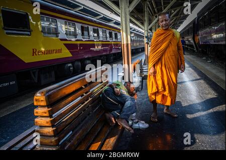 Buddhist monk and sleeping man, Hua Lamphong Railway Station, Bangkok, Thailand Stock Photo